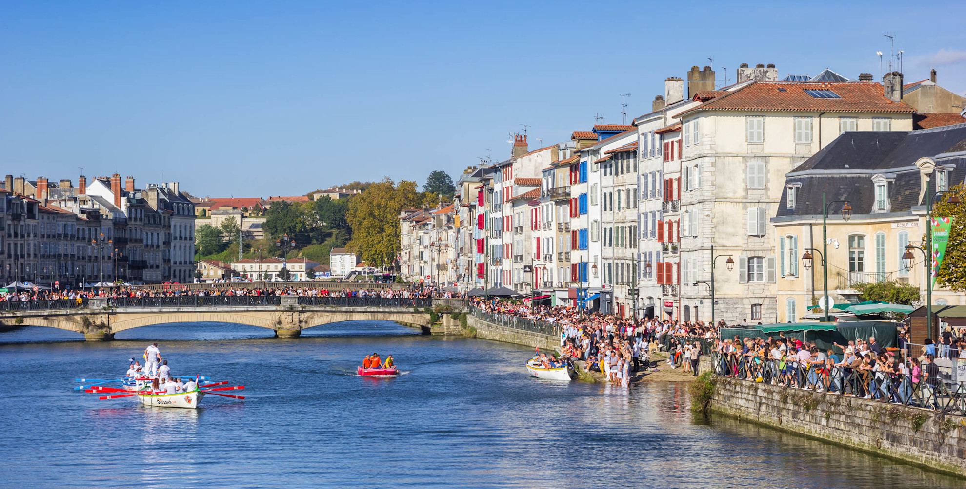 People enjoy the sun while watching the boat race in Bayonne