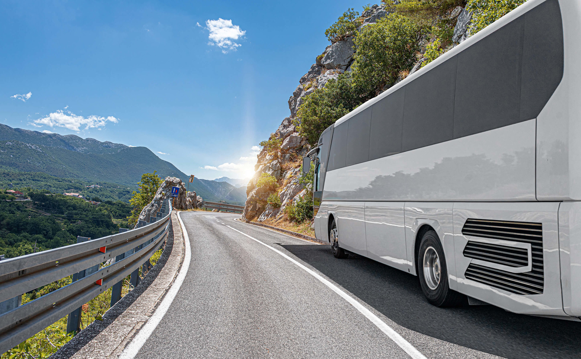 A white coach rides along the highway against the backdrop of a beautiful landscape