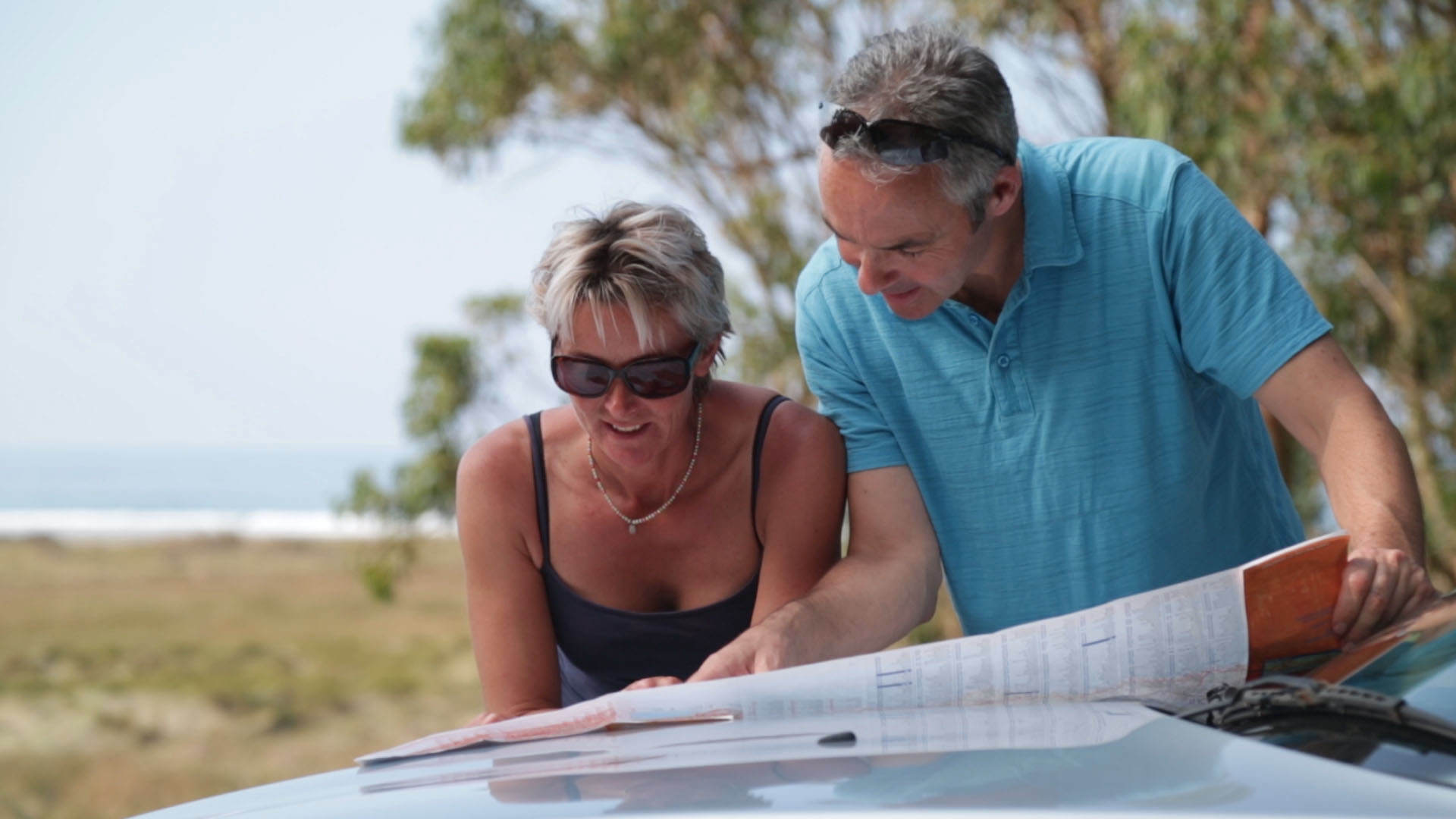 A photo of a couple studying a map over the bonnet of a car