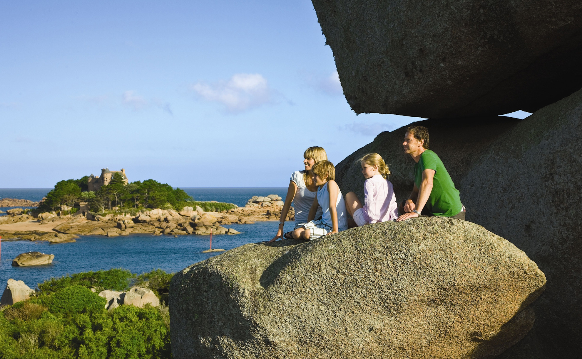 A family sitting on rocks at Ploumanac'h on the Pink Granite Coast in Brittany