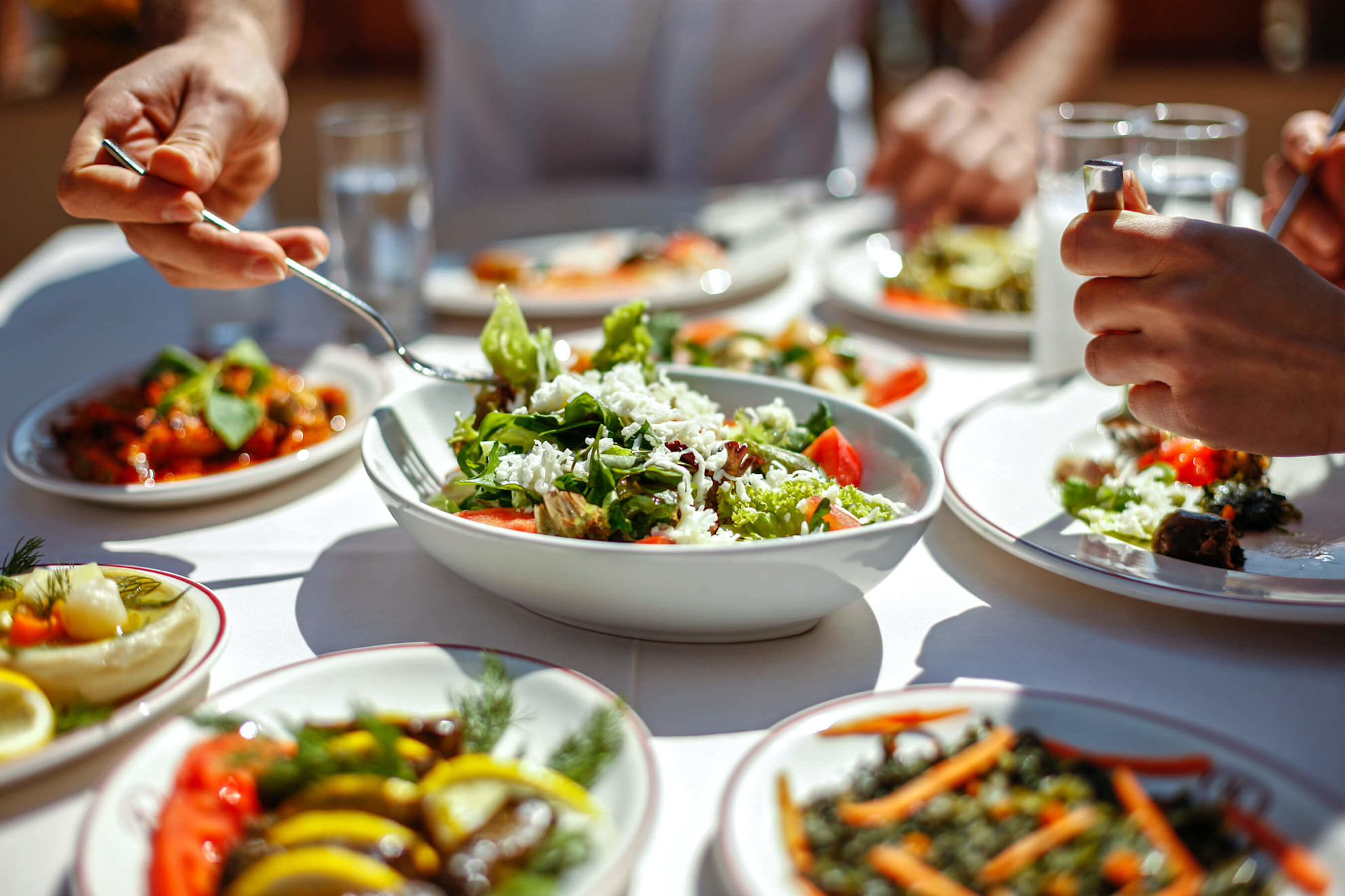 Couple eating lunch with fresh salad and appetizers