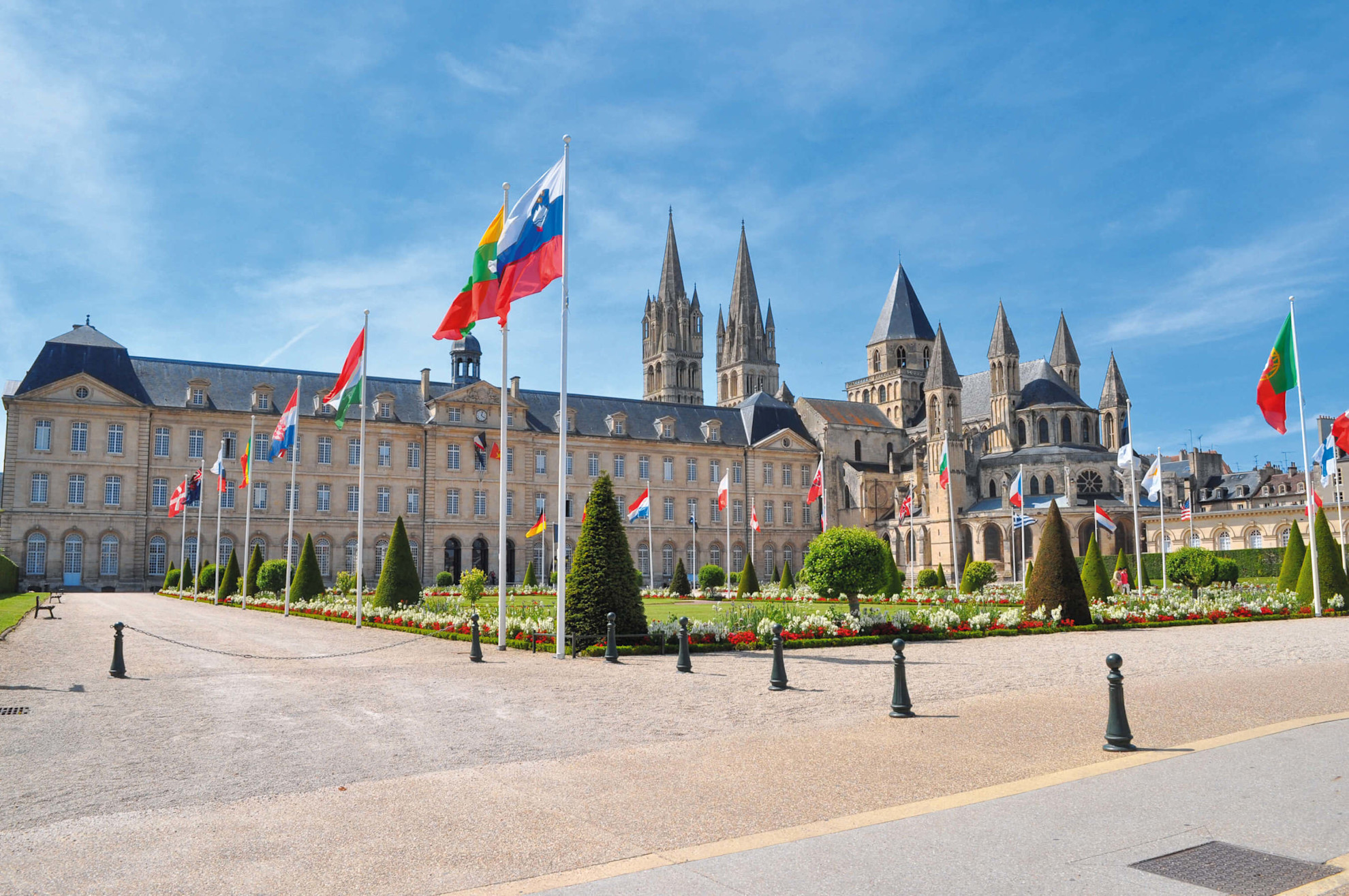 A view of the Abbaye aux hommes in Caen with flags and park