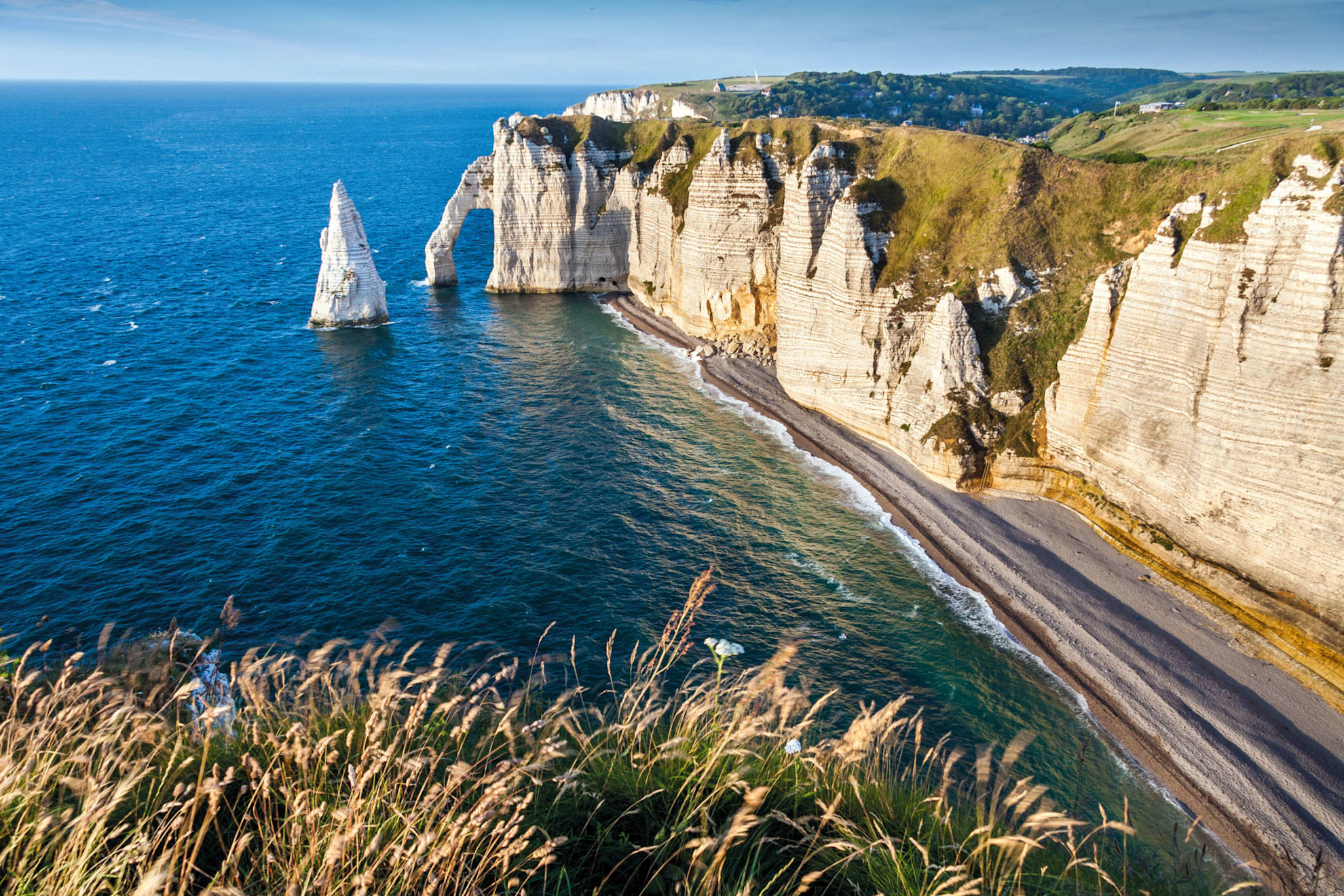 A photo of the cliffs at Etretat surrounded by the sea and a beach