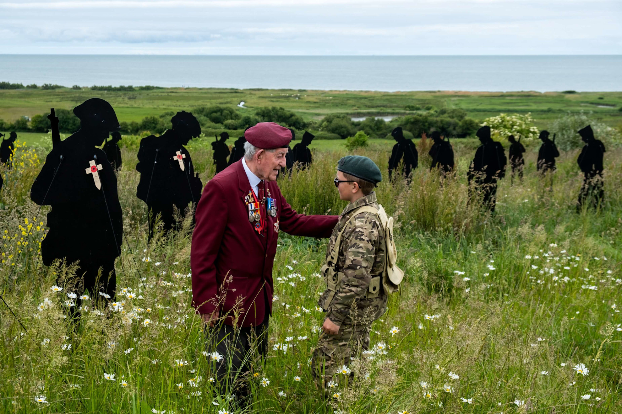 Veteran and child surrounded by the Standing with Giants at the British Normandy Memorial © British Normandy Memorial